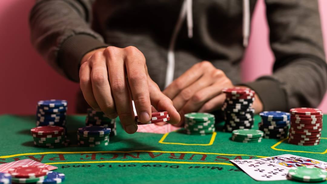 A blackjack player placing an insurance bet. He is surrounded by stacks of casino chips.