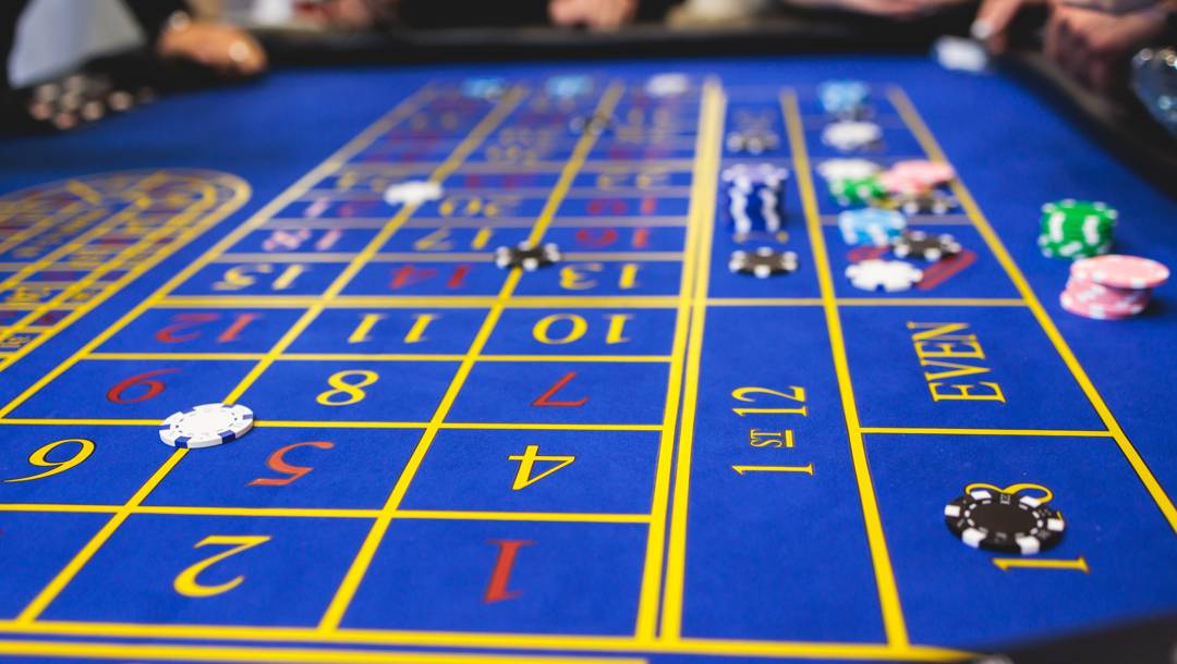 A close-up of a blue roulette table with bets placed.