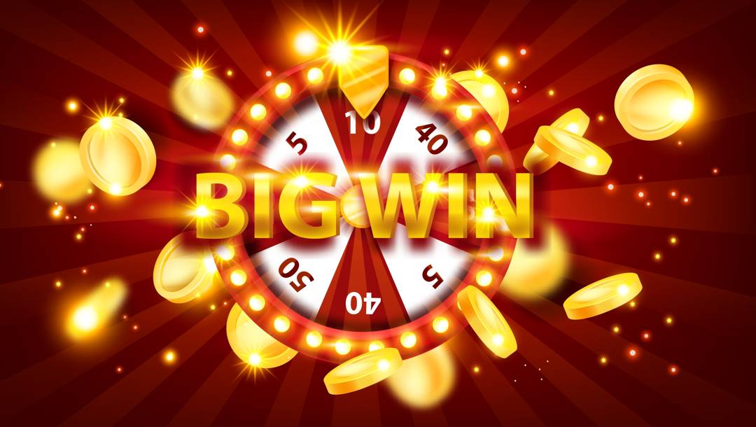 A red and white prize wheel surrounded by bright lights and gold coins. The words “Big Win” are across the centre of the wheel.