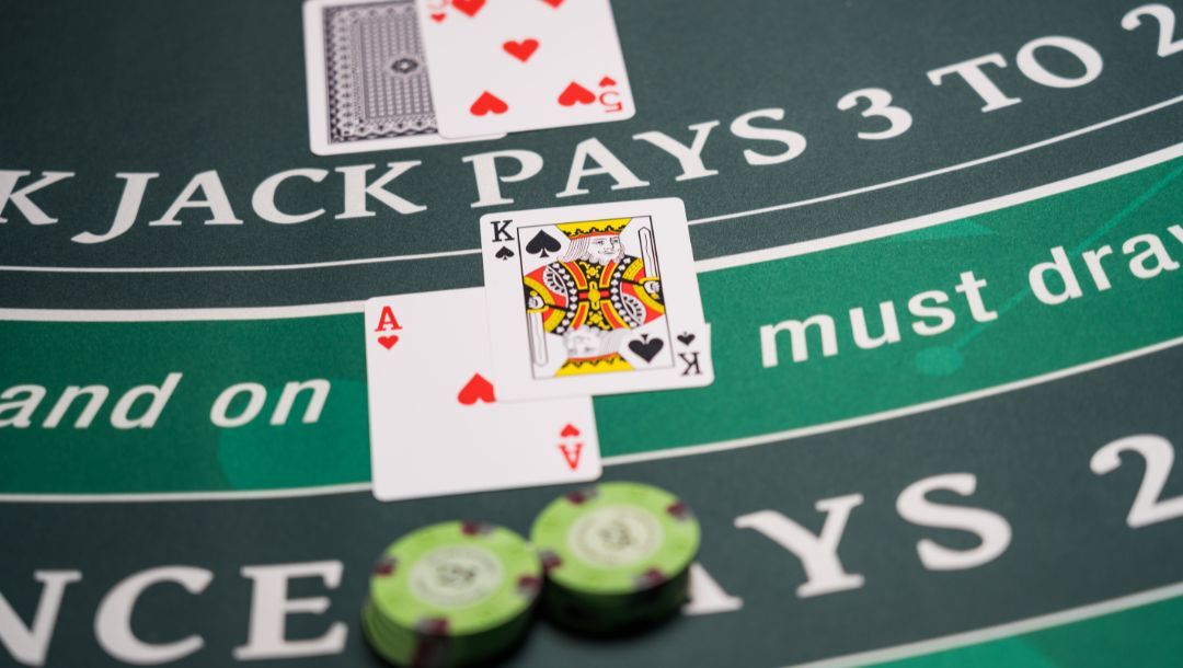 A blackjack hand showing a natural 21 with an ace and king, positioned beside betting chips on the felt and highlighting the game's highest-paying standard hand.