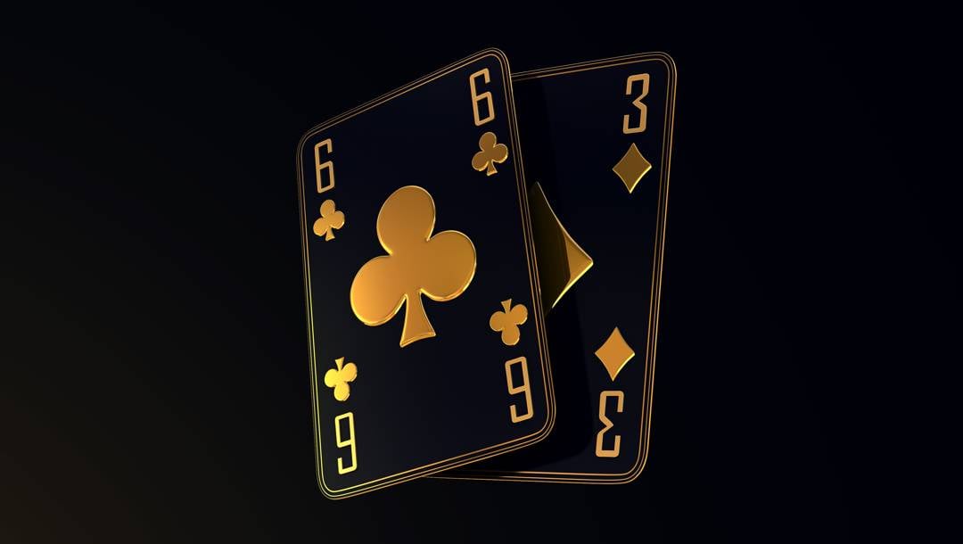 Two black-and-gold playing cards, a six of clubs and a three of diamonds, overlap against a dark background.