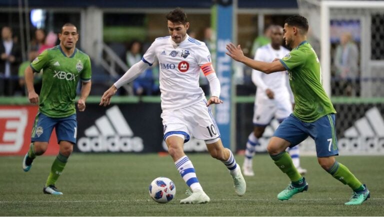 Montreal Impact midfielder Ignacio Piatti, center, dribbles past Seattle Sounders midfielder Cristian Roldan, right.