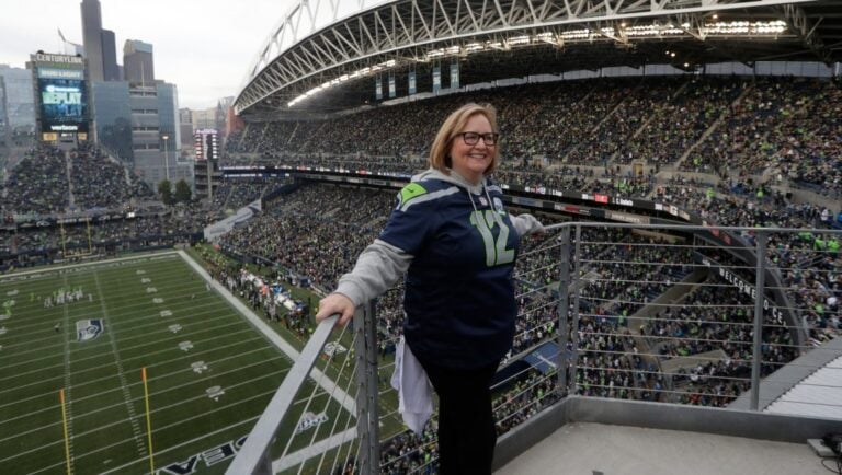 Seattle Seahawks owner Jody Allen stands on a balcony at CenturyLink Field after she raised the 12th man flag before the team's NFL football game against the Los Angeles Rams, Thursday, Oct. 3, 2019, in Seattle.