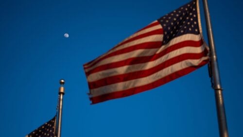 The moon is seen behind American flags on the National Mall, Friday, Feb. 27, 2026, in Washington.