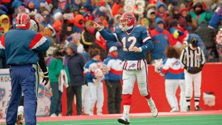 Buffalo Bills quarterback Jim Kelly points to the Bills bench after throwing a touchdown pass to receiver Bill Brooks in the fourth quarter against the Los Angeles Raiders at Orchard Park, N.Y., Jan. 15, 1994.