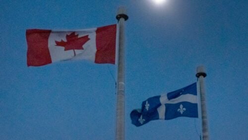 The moon covers the sun during a total solar eclipse, as Canadian and Quebec flags fly, as seen from Bishop's University in Sherbrooke, Quebec, Monday, April 8, 2024.