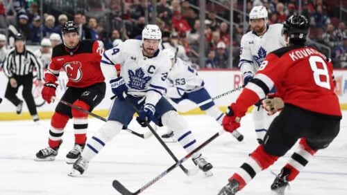 Toronto Maple Leafs center Auston Matthews (34) controls the puck in front of New Jersey Devils defenseman Johnathan Kovacevic (8) during the first period of an NHL hockey game Wednesday, March 4, 2026, in Newark, N.J.