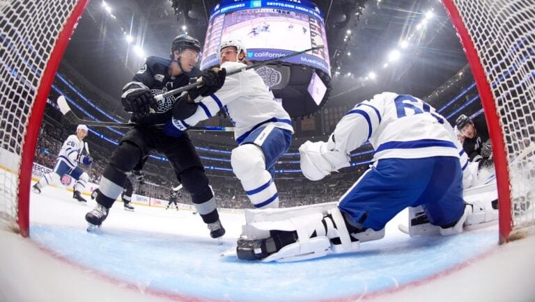Los Angeles Kings left wing Trevor Moore, left, and Toronto Maple Leafs defenseman Simon Benoit, center, battle in front of the net as goaltender Joseph Woll, right, sits on goal during the first period of an NHL hockey game Saturday, April 4, 2026, in Los Angeles.