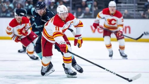 Calgary Flames center Mikael Backlund (11) skates with the puck past Seattle Kraken defenseman Vince Dunn (29) during an NHL hockey game Saturday, April 11, 2026, in Seattle.