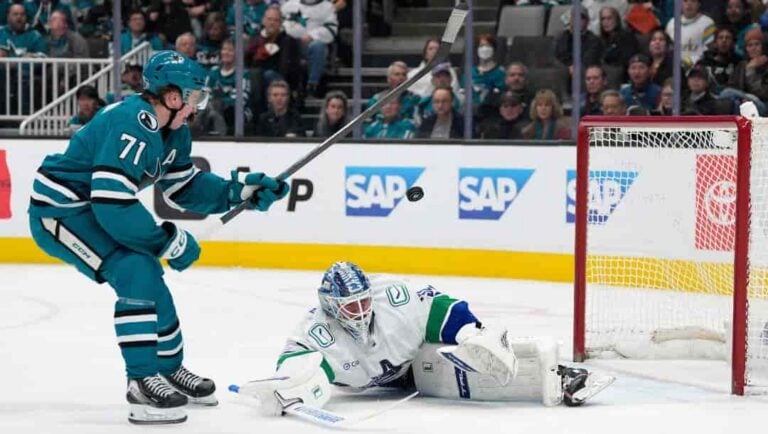 Vancouver Canucks goaltender Kevin Lankinen, right, blocks a shot by San Jose Sharks center Macklin Celebrini (71) during the first period of an NHL hockey game in San Jose, Calif., Saturday, April 11, 2026.